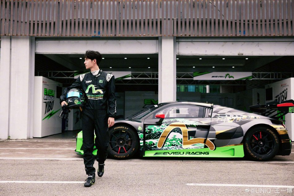 王一博微博分享赛车场随拍照 黑绿赛车服单手拿头盔帅气十足